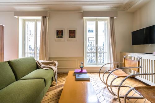ein Wohnzimmer mit einem grünen Sofa und einem Tisch in der Unterkunft Pied A Terre - Palestro in Paris