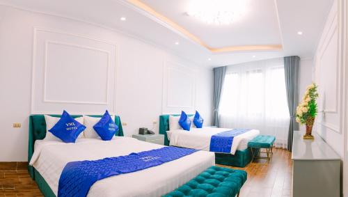 two beds in a room with blue and white at Khách sạn VHL Hà Nam in Phủ Lý