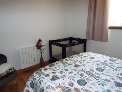 a bedroom with a bed with a floral comforter at Gîte La Peyre in Le Grand-Bourg