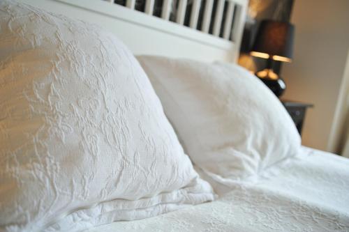 a bed with white sheets and a pillow at Sztygarka. Pensjonat Pod Wieżą Katowice Chorzów in Chorzów
