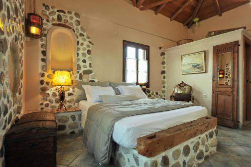 a bedroom with a large bed with a stone wall at Archontiko Art Hotel in Galaxidi
