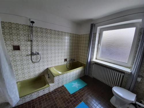 a bathroom with a green tub and a toilet at Fewo Rose in Norden