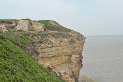 a building on the side of a cliff next to the water at Apartament Crina in Jurilovca