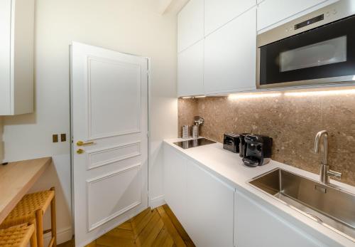 una cocina con armarios blancos y fregadero en Appartement de standing 1 – tour Eiffel/Invalides en París