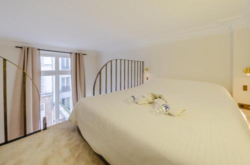 ein großes weißes Bett mit ausgestopftem Tier drauf in der Unterkunft Appartement de standing 1 – tour Eiffel/Invalides in Paris