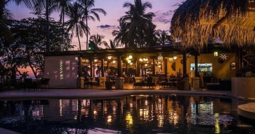 a resort with a pool in front of a building at Sunset del Mar Beach Resort in Esterillos Este