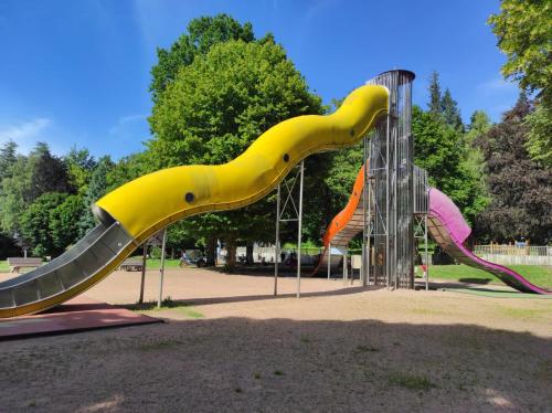 un toboggan en forme de dinosaure sur une aire de jeux dans l'établissement L'escapade, à La Bourboule
