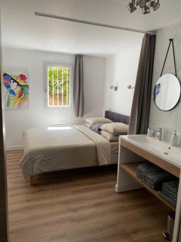 - une chambre avec un lit, un miroir et un lavabo dans l'établissement Domaine des Restanques, suite parentale ,vue mer., à Grimaud