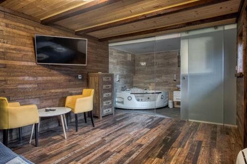 a bathroom with a tub and a tv on a wall at Ribarski konaci in Doboj