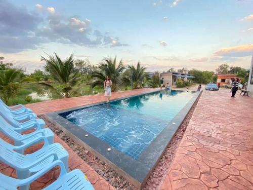 a large swimming pool with two blue chairs next to it at BN Resort in Ban Nong Chum Saeng