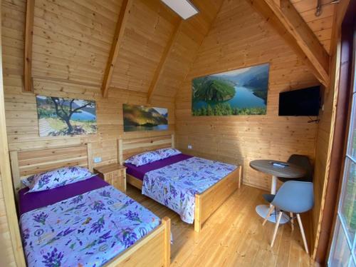 een kamer met 2 bedden en een tafel in een hut bij 5 Stinet in Koman