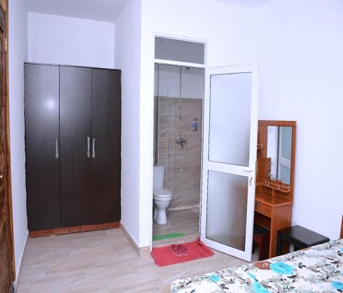 a bathroom with a toilet and a glass door at Mtwapa Pride Apartment 4th Floor in Mtwapa