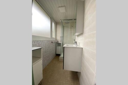 een witte badkamer met een wastafel en een douche bij RESIDENCE ABOUT STUDIO lumineux proche plage in Duinkerke