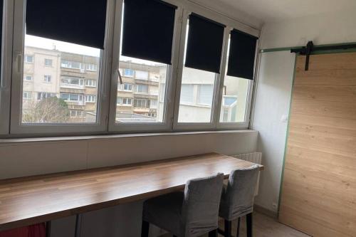 een kamer met een houten tafel en 2 ramen bij RESIDENCE ABOUT STUDIO lumineux proche plage in Duinkerke