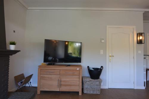 a living room with a flat screen tv on a wooden dresser at Villa O'Soleil in De Panne
