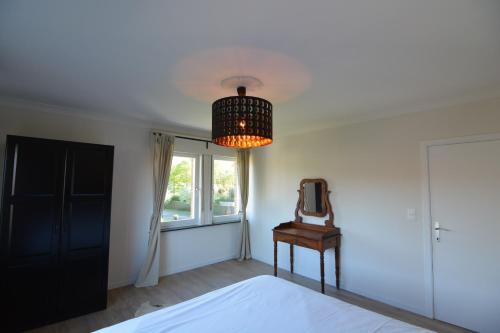 a bedroom with a bed and a mirror and a chandelier at Villa O'Soleil in De Panne