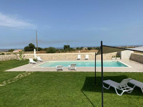 - une piscine avec 2 chaises longues et une table dans l'établissement Casale Zacco Micciò, à Rosolini