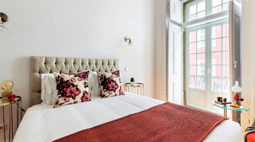 a bed with a white comforter and pillows on it at LeL Madalena GuestHouse in Lisbon