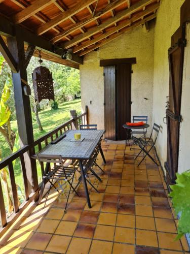 un patio avec une table et des chaises sur un porche dans l'établissement gîte la bergerie, à Sarlat-la-Canéda