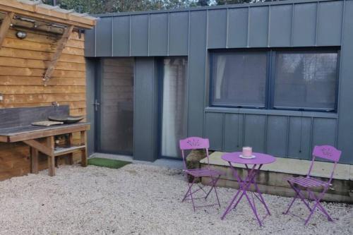 a patio with purple chairs and a table and a grill at Gite La Basse-Cour in Cordemais