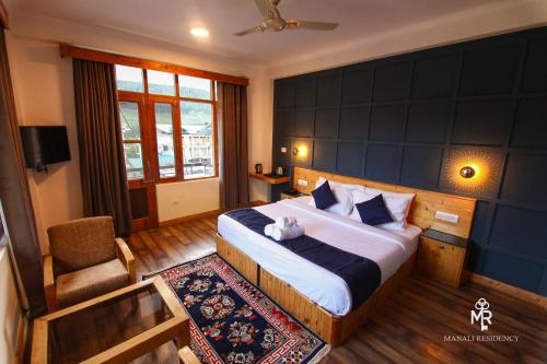 a bedroom with a king sized bed and a chair at Manali residency in Manāli