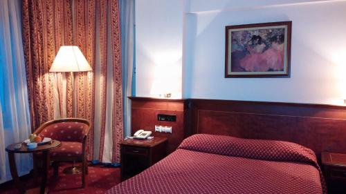 アンカラにあるOzilhan Hotelの赤いベッドと椅子が備わるホテルルームです。