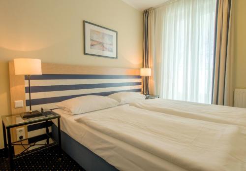 ein Schlafzimmer mit einem großen weißen Bett und einem Fenster in der Unterkunft Haus Seeblick Wohnung 326 in Zingst