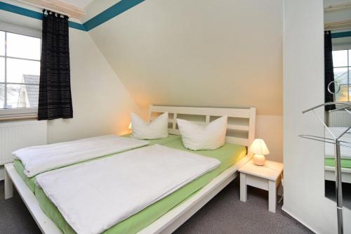 a bedroom with a bed with white sheets and pillows at Grode Stuw in Zingst