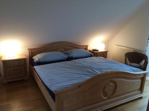 a bedroom with a wooden bed with blue sheets and two lamps at Haus Zeesenboot Luv in Hiddensee