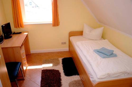 ein kleines Schlafzimmer mit einem Bett, einem Schreibtisch und einem Fenster in der Unterkunft Mühlenstrasse 19 - Wohnung 3 in Zingst