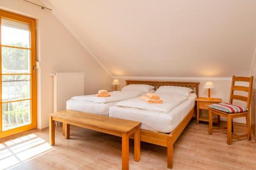 a bedroom with two beds and a bench and a window at Ferienpark Freesenbruch Reihenhaus 8 - Zum Meer in Zingst
