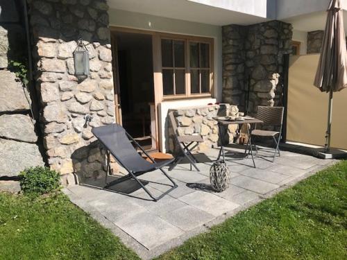 a patio with a table and chairs and a stone wall at Residenz am Berg in Jochberg