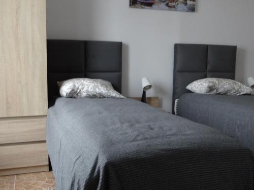 a bedroom with two beds with gray sheets at Hotel Apartamenty 72 in Płock