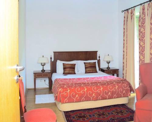 een slaapkamer met een bed met een rode deken en 2 tafels bij Mosteiro De S. Cristovao De Lafoes in São Cristóvão de Lafões