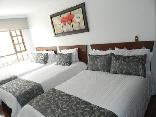 Habitación de hotel con 2 camas y una foto en la pared en Hotel Salitre Real, en Bogotá