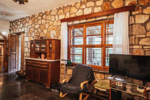 a living room with a tv and a stone wall at Villa Polytimi in Vonitsa
