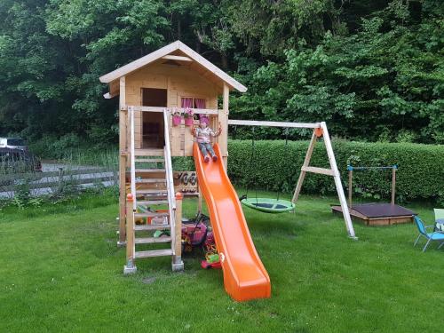 a playground with an orange slide and a play house at Apart Dahuam in Aschau