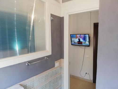 a bathroom with a tv on a wall with a window at Atlantide in Muravera