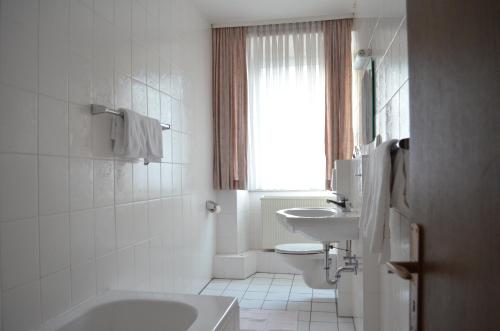 ein Bad mit einem Waschbecken, einem WC und einem Fenster in der Unterkunft Hotel Drei Schweizer in Neuwied