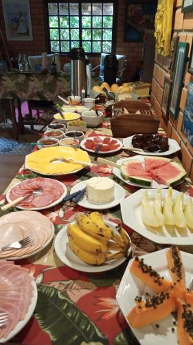 ein langer Tisch mit Tellern voller Essen darauf in der Unterkunft Pousada Rosa & Canela in Praia do Rosa