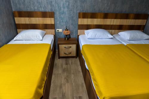 two beds in a small room with yellow sheets at LIONS APARTMENT in Ureki