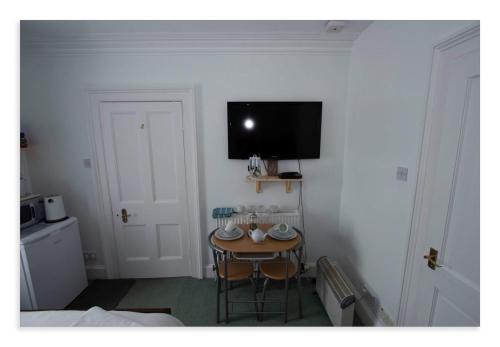 a room with a small table with a tv on the wall at Cornmill House, With Outstanding Sea Views In Garlieston in Garlieston