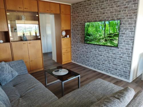 een woonkamer met een bank en een bakstenen muur bij Ferienwohnung Harz Valley -Mit Fernblick in den Harz. in Goslar