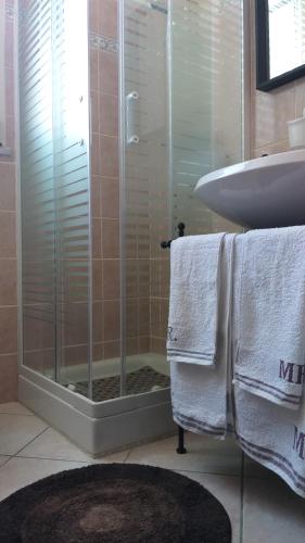 a bathroom with a shower and a sink and towels at Fiori e farfalle apartment in Caprarola