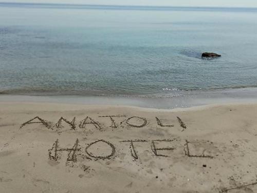 a sign written in the sand on a beach at Anatoli Hotel in Agia Marina Aegina