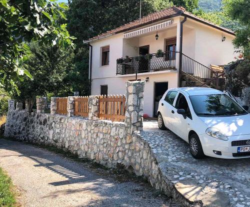 een witte auto geparkeerd voor een huis bij Apartman Popović in Virpazar