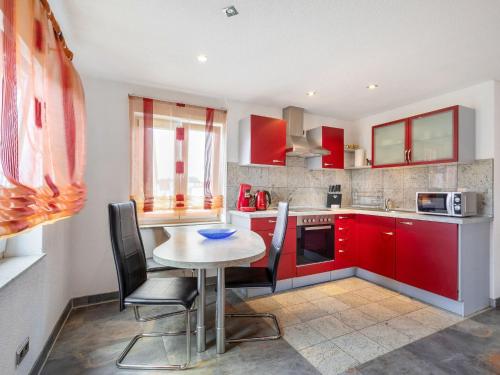 a kitchen with red cabinets and a table and chairs at Apartment only 100 m from Althausen Castle 