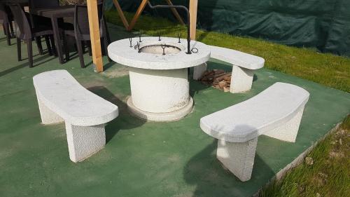 three white benches and a fountain on the grass at Angyal apartman in Cserkeszőlő