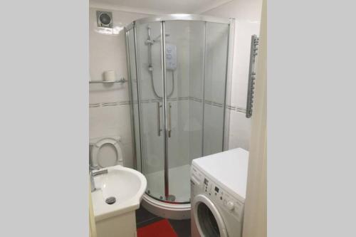 uma casa de banho com um chuveiro e uma máquina de lavar roupa em Private Studio home away from home ... em Hackbridge