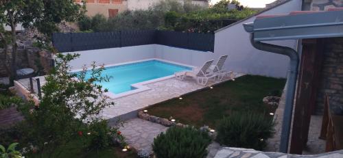 a small swimming pool in a backyard with a patio at Kamena kuća Rutar in Pridraga